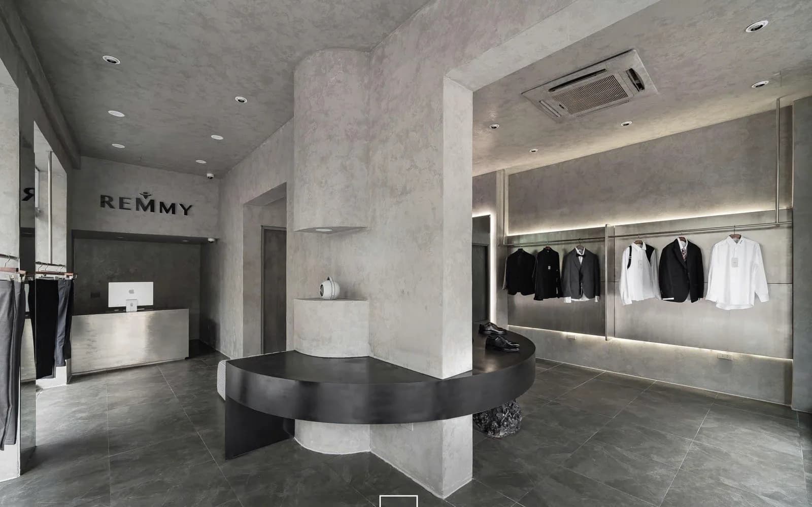 Nội thất showroom REMMY 48 Phố Huế với biển hiệu REMMY, bàn trưng bày cong và khu treo trang phục